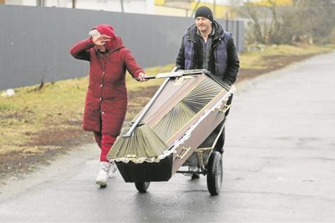 Dos personas transportan un ataúd en una zona atacada por bombardeos en la pequeña ciudad de Borodyanka, cerca de Kiev.